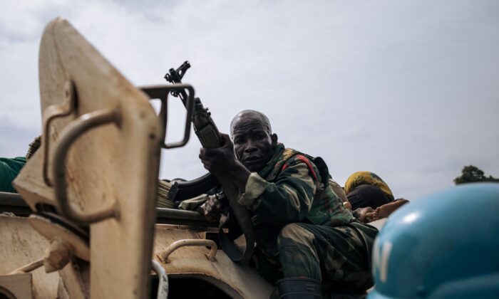 A Congolese soldier protects himself against CODECO militiamen attempting to bury the bodies of people killed in Dhedja, 60 kilometers from Bunia, the provincial capital of Ituri in Democratic Republic of Congo, on Dec. 19, 2021. (Alexis Huguet/AFP via Getty Images)
