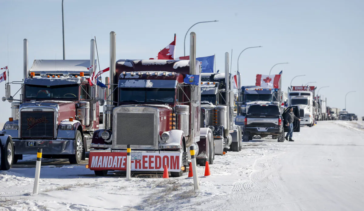 Protesters demonstrating against COVID-19 mandates gather as a truck convoy blocks the highway at the U.S. border crossing in Coutts, Alta., Canada, on Feb. 2, 2022. (The Canadian Press/Jeff McIntosh)