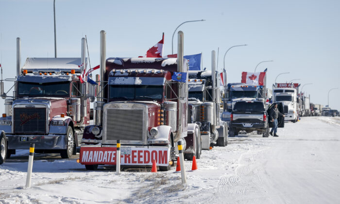 Protesters demonstrating against COVID-19 mandates gather as a truck convoy blocks the highway at the U.S. border crossing in Coutts, Alberta, on Feb. 2, 2022. (The Canadian Press/Jeff McIntosh)