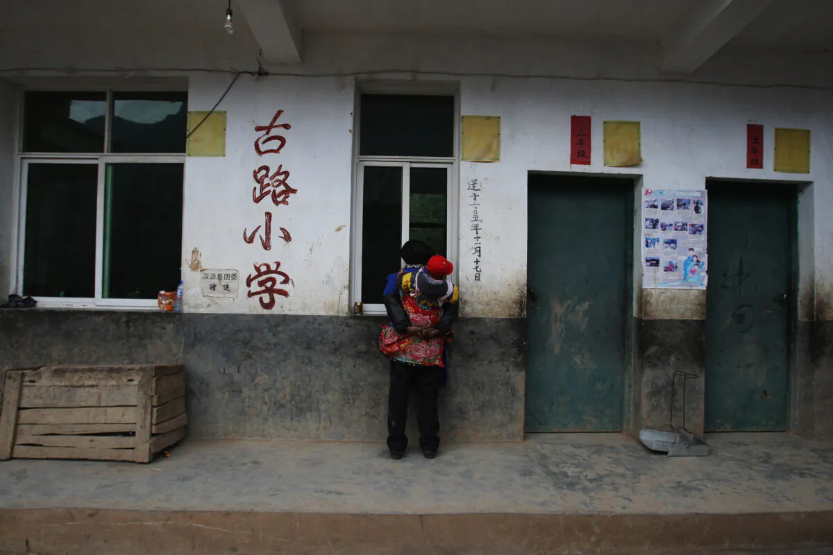 A Yi ethnic elderly woman watches students taking part in a lesson at the school in the village of Gulucan on Nov. 17, 2008 in Hanyuan county, Sichuan province, China. (Guang Niu/Getty Images)