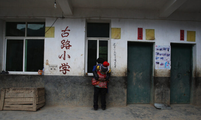 A Yi ethnic elderly woman watches students taking part in a lesson at the school in the village of Gulucan on Nov. 17, 2008 in Hanyuan county, Sichuan province, China.  (Guang Niu/Getty Images)