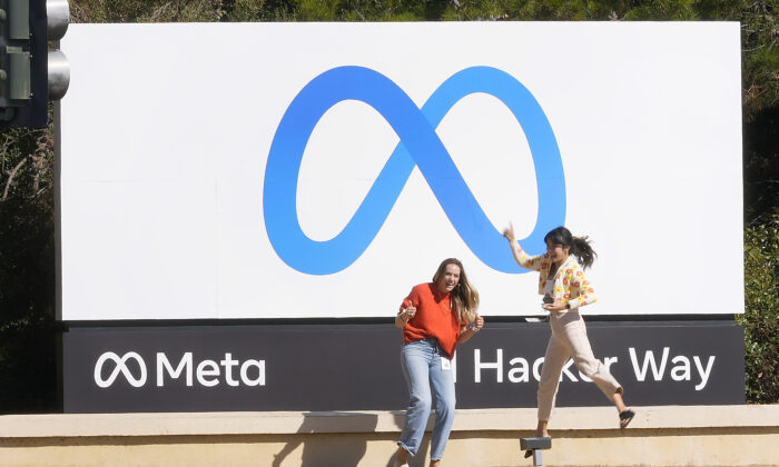 Facebook employees take a photo with the company's new name and logo outside its headquarters in Menlo Park, Calif., on Oct. 28, 2021. (Tony Avelar/AP Photo)