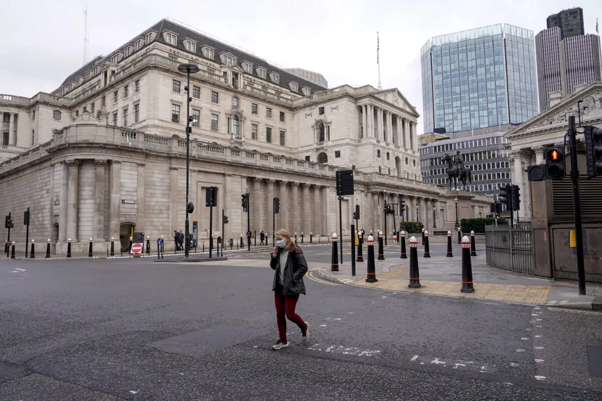 A woman crosses a road outside the Bank of England in London on Dec. 13, 2021. (Alberto Pezzali/AP Photo)