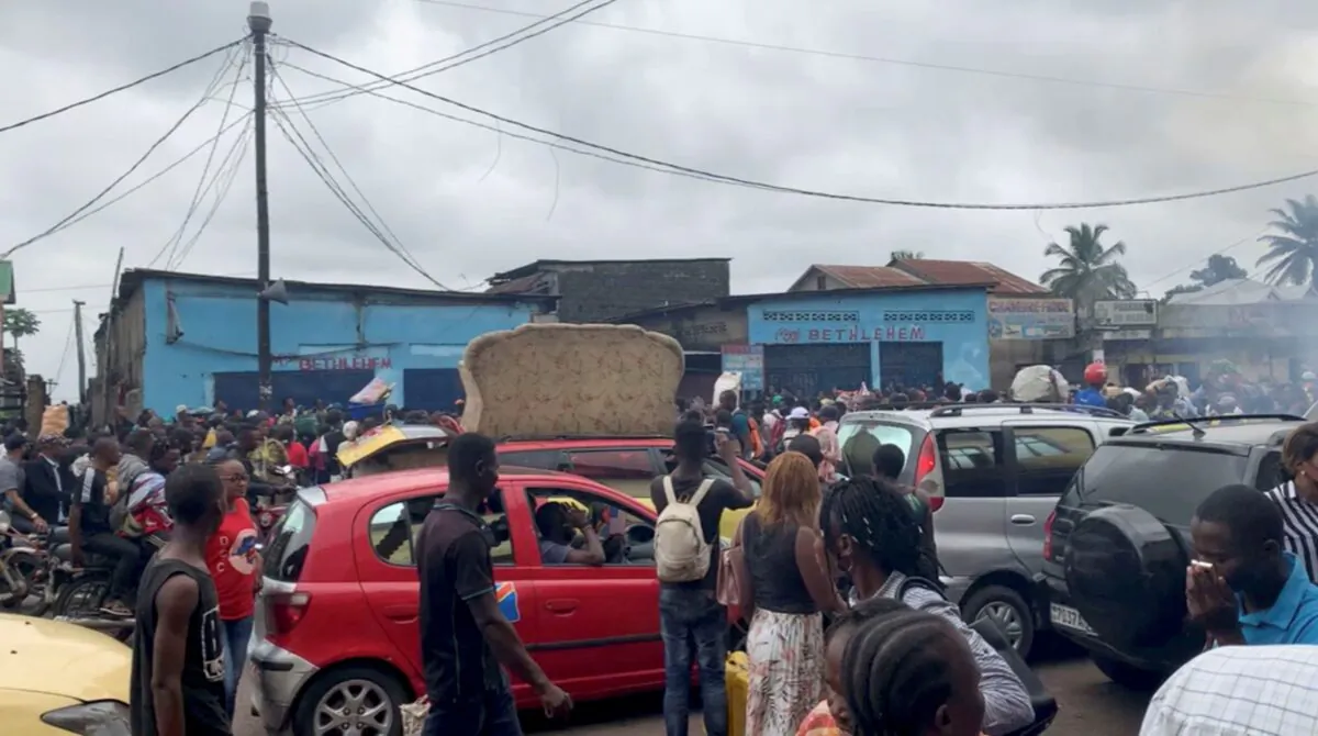 People walk amid traffic near the site where a high-tension power cable snapped and fell on houses and a market on the outskirts of Kinshasa, the Democratic Republic of the Congo, on Feb. 2, 2022, in this still image taken from video obtained from social media. (Pepele News/via Reuters)