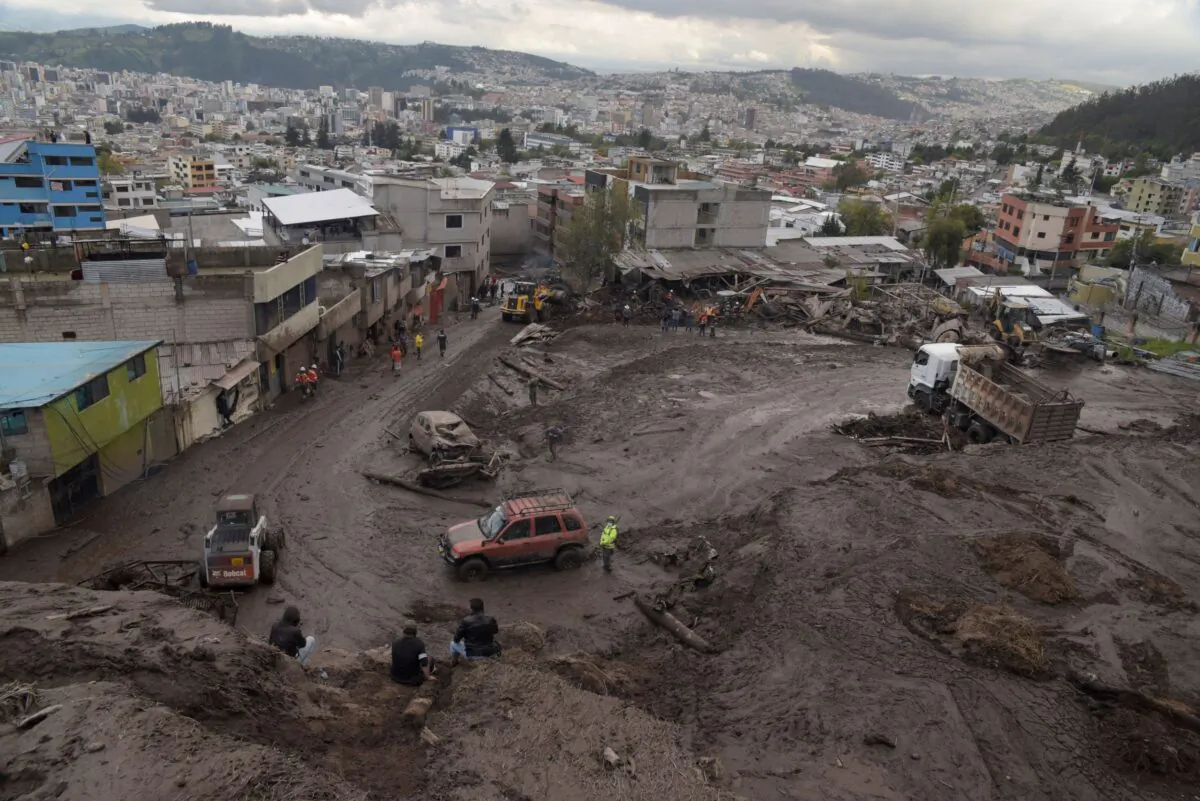 People, soldiers, and rescue workers help with clean-up operations after torrential rains caused a landslide, sending mud and rocks down on residences and affecting electricity provision, in Quito, Ecuador, on Feb. 1, 2022. (Johanna Alarcon/Reuters)