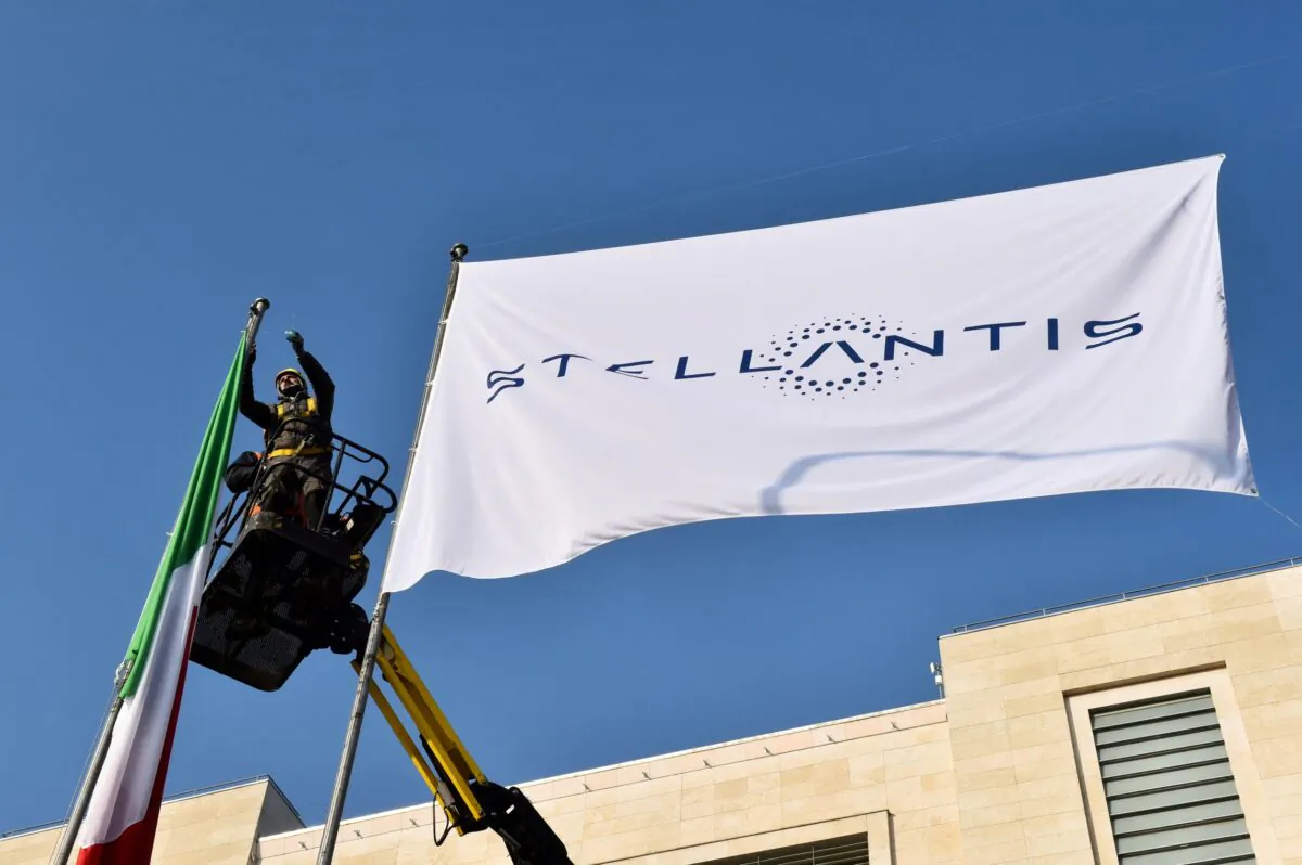 Workers install a flag with the logo of Stellantis at the main entrance of FCA Mirafiori plant in Turin, Italy, on Jan. 18, 2021. (Massimo Pinca/Reuters)