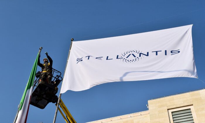Workers install a flag with the logo of Stellantis at the main entrance of FCA Mirafiori plant in Turin, Italy, on Jan. 18, 2021. (Massimo Pinca/Reuters)