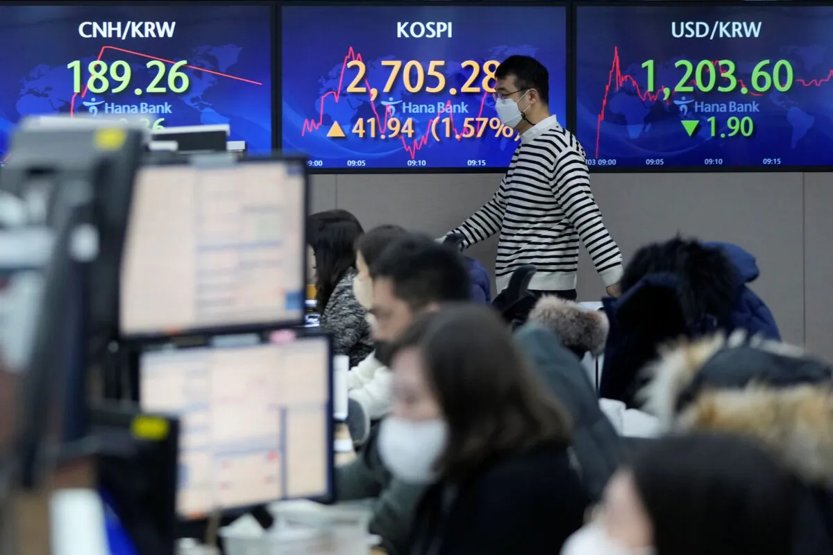 A currency trader passes by screens showing the Korea Composite Stock Price Index (KOSPI) and the foreign exchange rate between U.S. dollar and South Korean won, right, at the foreign exchange dealing room of the KEB Hana Bank headquarters in Seoul, South Korea, on Feb. 3, 2022. (Ahn Young-joon/AP Photo)