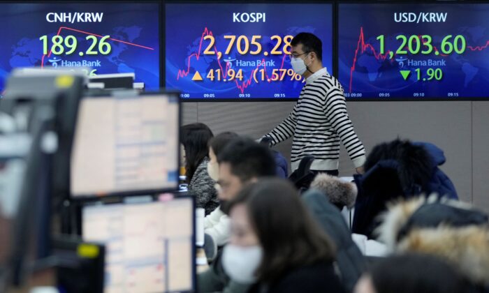 A currency trader passes by screens showing the Korea Composite Stock Price Index (KOSPI) and the foreign exchange rate between U.S. dollar and South Korean won, right, at the foreign exchange dealing room of the KEB Hana Bank headquarters in Seoul, South Korea, on Feb. 3, 2022. (Ahn Young-joon/AP Photo)