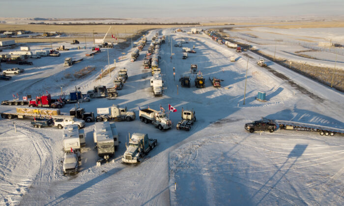 Protesters demonstrating against COVID-19 mandates gather as a truck convoy blocks the highway at the U.S. border crossing in Coutts, Alta., on Feb. 2, 2022. (The Canadian Press/Jeff McIntosh)