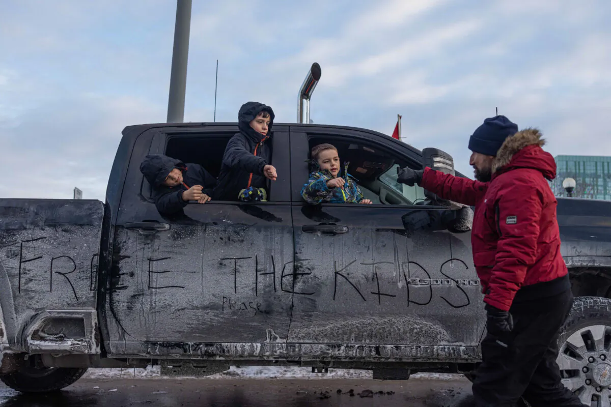 Children lean out of a vehicle to fist-pump a passing protester, in Ottawa on Jan. 30, 2022. (Alex Kent/Getty Images)