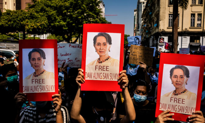 Protesters hold up posters featuring Aung San Suu Kyi and make three-finger salutes in Yangon, Myanmar on Feb. 08, 2021. (Stringer/Getty Images)