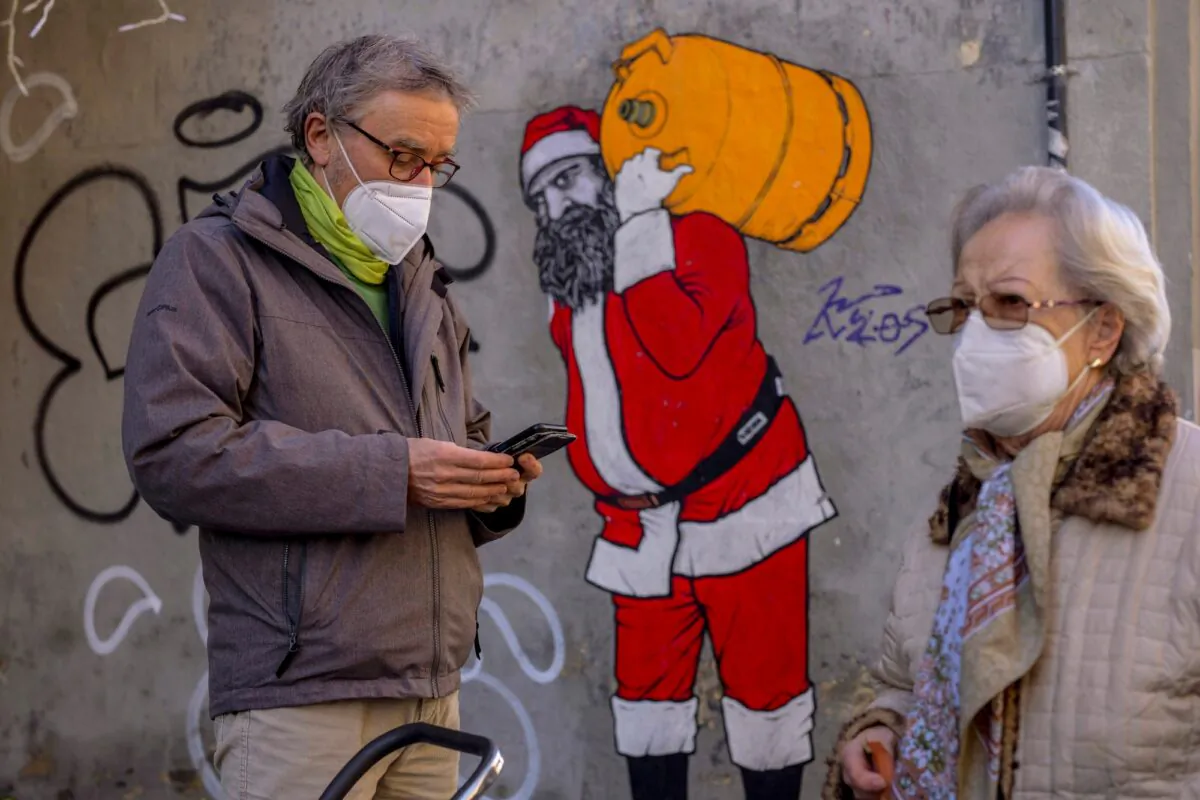 A man and woman wearing FFP2 masks to curb the spread of COVID-19 are seen in front of a mural depicting Santa Claus, in Madrid, on Jan. 12, 2022. (Manu Fernandez/AP Photo)