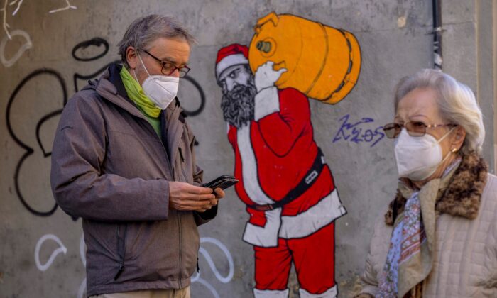 A man and woman wearing FFP2 masks to curb the spread of COVID-19 are seen in front of a mural depicting Santa Claus, in Madrid, on Jan. 12, 2022. (Manu Fernandez/AP Photo)