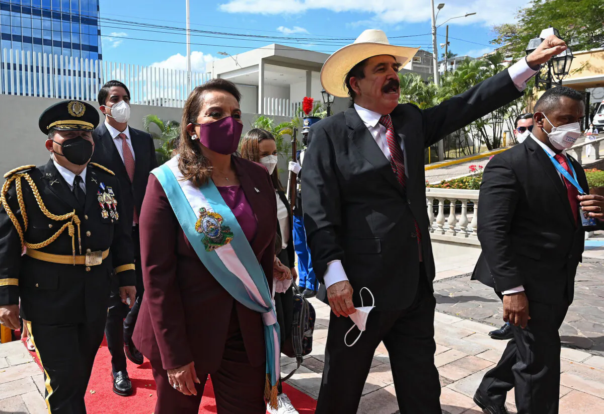 Hondura's new president Xiomara Castro (C) walks next to her husband, former president Manuel Zelaya (R), as he raises his clenched fist while they arrive at the presidential house in Tegucigalpa on Jan. 27, 2022. (Orlando Sierra/AFP via Getty Images) 
