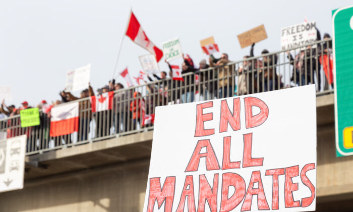 People on a highway overpass support the Freedom Rally and the protest of the truck drivers against vaccine mandates, in Surrey, Vancouver, British Columbia, Canada, on Jan. 29, 2022. (EdgarBullon/Shutterstock)
