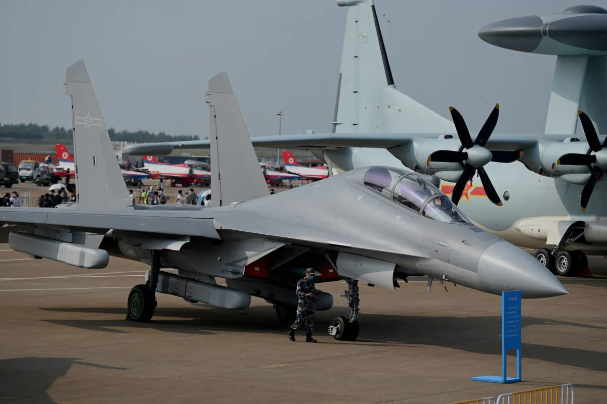 A military personnel walks past Shenyang Aircraft Corporation's J-16 multirole strike fighter for the People's Liberation Army Air Force (PLAAF) at the 13th China International Aviation and Aerospace Exhibition in Zhuhai, southern China's Guangdong Province on Sept. 28, 2021. (Noel Celis/AFP via Getty Images)
