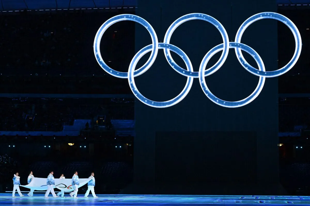 The Olympic flag is carried under the Olympic rings during the opening ceremony of the Beijing 2022 Winter Olympic Games, at the National Stadium, known as the Bird's Nest, in Beijing, China on Feb. 4, 2022. (Ben Stansall/AFP via Getty Images)