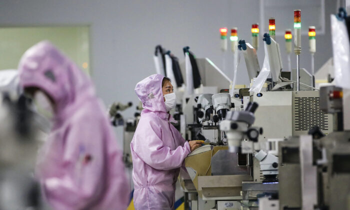 Chinese employees wearing protective masks and suits work on a smart chip production line in Sihong in China's eastern Jiangsu Province on February 16, 2020.  (STR / AFP)