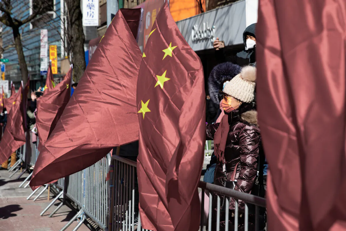 People stand next to Chinese flags along Flushing's Main Street at the Chinese New Year Parade in New York, on Feb. 5, 2022. (Chung I Ho/The Epoch Times)