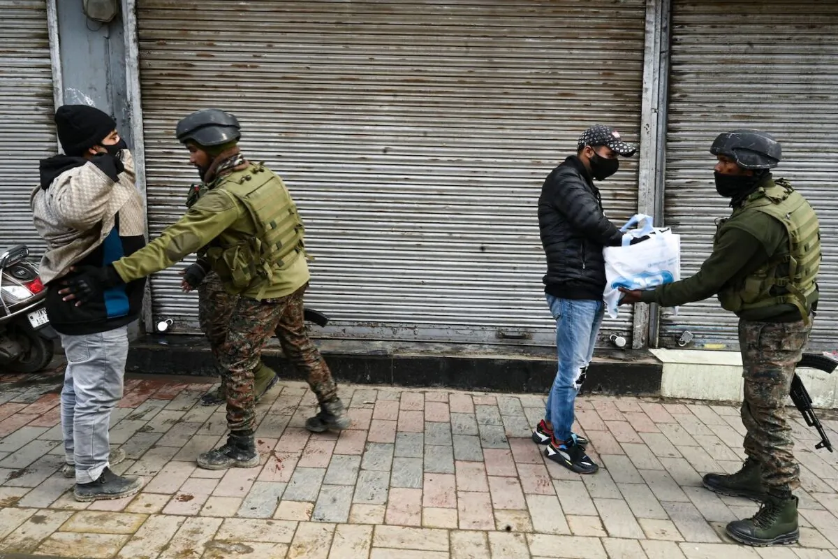 Indian government forces frisk pedestrians along a road in Srinagar on Jan. 25, 2022, after suspected militants threw a hand grenade towards government forces. (Tauseef Mustafa/AFP via Getty Images)