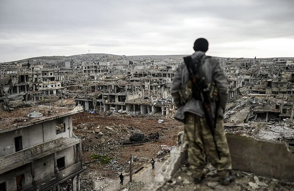 A 25-year-old Kurdish marksman, stands atop a building as he looks at the destroyed Syrian town of Kobane, also known as Ain al-Arab, on Jan. 30, 2015. (Bulent Kilic/AFP via Getty Images)