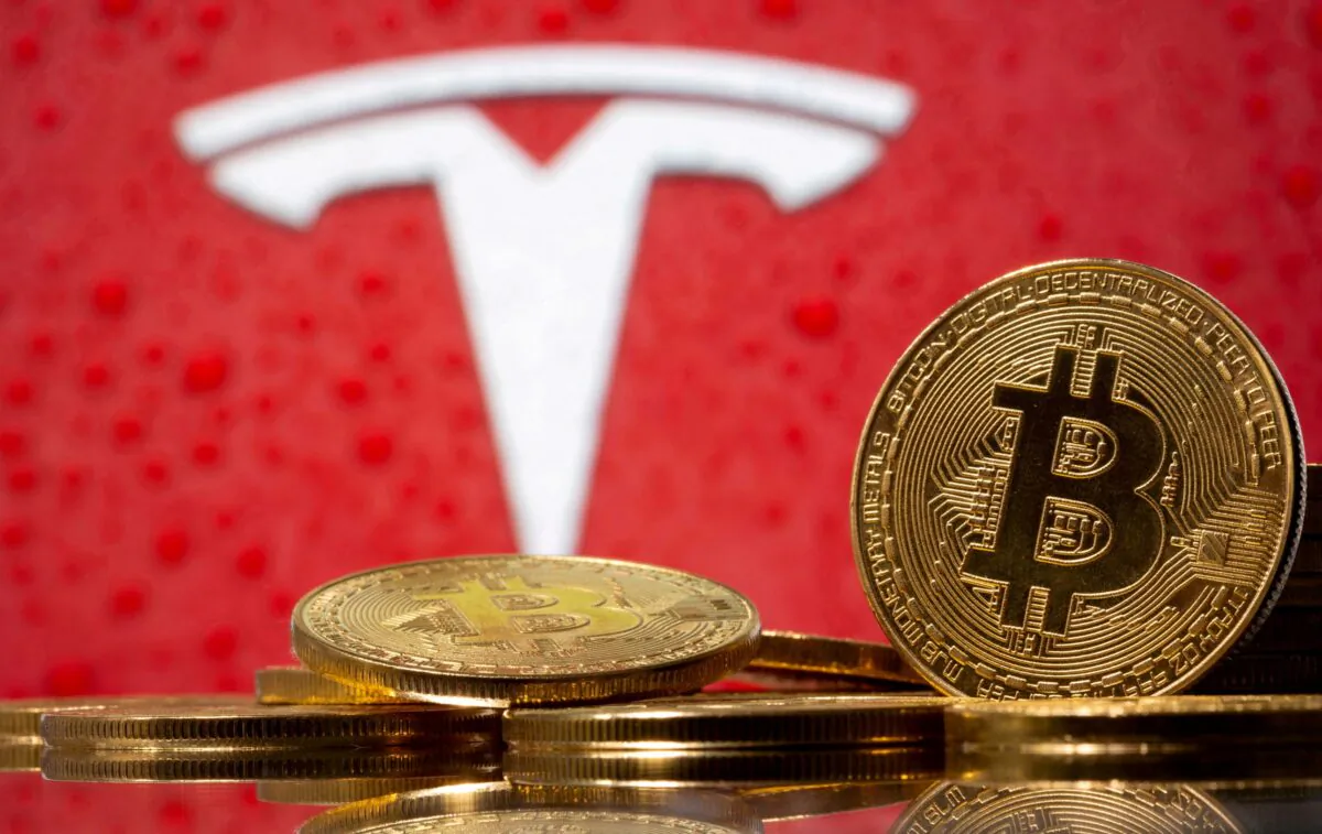 Representations of virtual currency bitcoin are seen in front of Tesla logo in this illustration taken, on Feb. 9, 2021. (Dado Ruvic/Reuters)