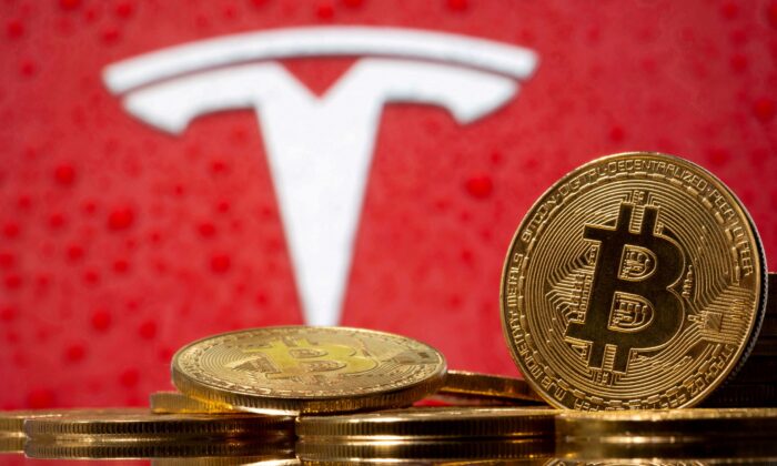 Representations of virtual currency bitcoin are seen in front of Tesla logo in this illustration taken, on Feb. 9, 2021. (Dado Ruvic/Reuters)