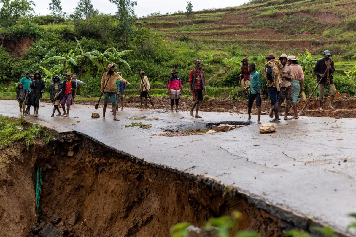 Locals stand on a damaged road following a landslide, as Cyclone Batsirai hits Madagascar, in Haute Matsiatra region, Madagascar, on Feb. 6, 2022. (Alkis Konstantinidis/Reuters)