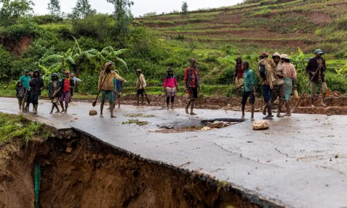 Locals stand on a damaged road following a landslide, as Cyclone Batsirai hits Madagascar, in Haute Matsiatra region, Madagascar, on Feb. 6, 2022. (Alkis Konstantinidis/Reuters)
