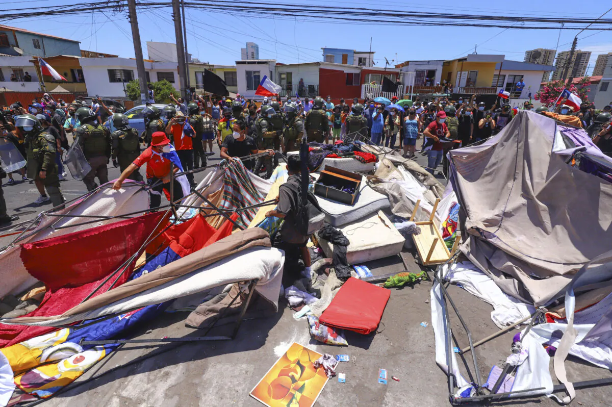 People destroy a makeshift camp of migrants during a protest against the increase of crime, which they claim is due to the presence of immigrants, in Iquique, Chile on Jan. 30, 2022. (Fernando Munoz/AFP via Getty Images)
