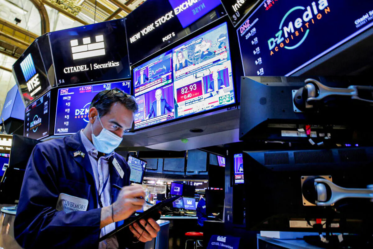 A trader works, as Federal Reserve Chair Jerome Powell is seen delivering remarks on screens, on the floor of the New York Stock Exchange (NYSE) in New York, on Jan. 26, 2022.  (Brendan McDermid/Reuters)