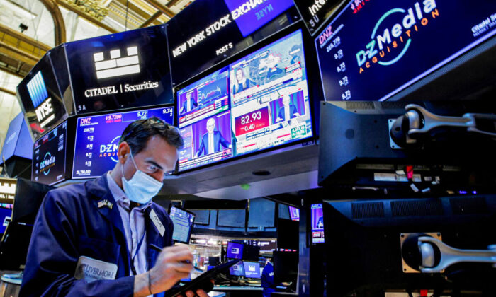 A trader works, as Federal Reserve Chair Jerome Powell is seen delivering remarks on screens, on the floor of the New York Stock Exchange (NYSE) in New York, on Jan. 26, 2022.  (Brendan McDermid/Reuters)