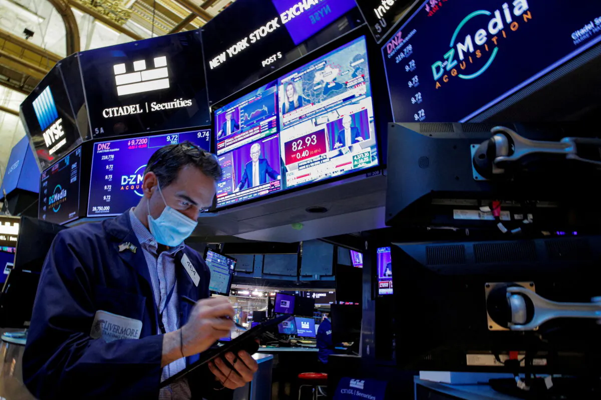 A trader works, as Federal Reserve Chair Jerome Powell is seen delivering remarks on screens, on the floor of the New York Stock Exchange (NYSE) in New York on Jan. 26, 2022.  (Brendan McDermid/Reuters)