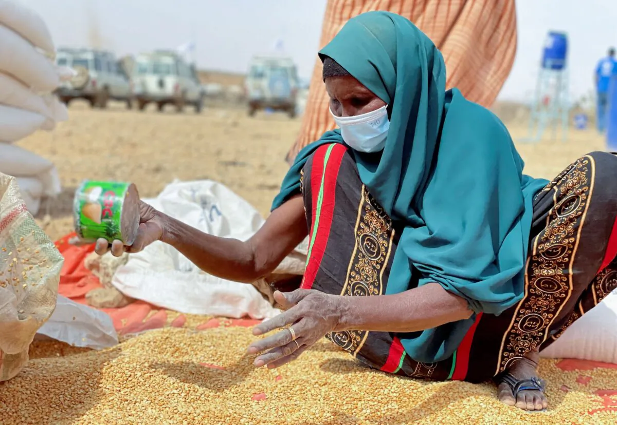 An Ethiopian woman sifts through distributed food supplies during a visit by World Food Programme (WFP) Regional Director Michael Dunford to a camp for the internally-displaced in Adadle, in the Somali Region of Ethiopia, on Jan. 22, 2022. (Claire Nevill/WFP via AP)