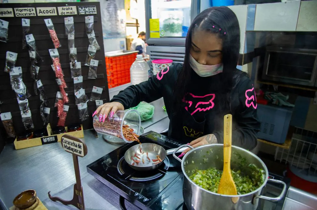 A young woman prepares maguey worms at a store of the San Juan market at the historic centre in Mexico City on August 3, 2021. (Photo by CLAUDIO CRUZ/AFP via Getty Images)