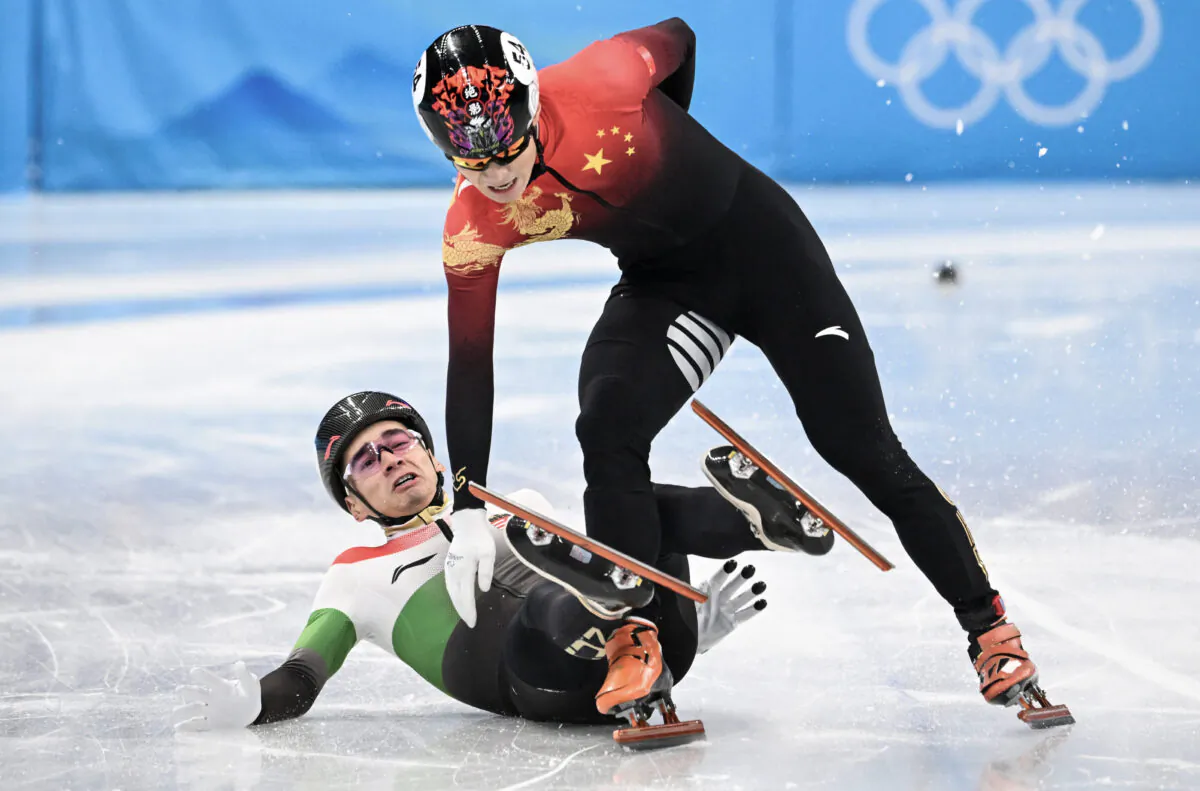 Hungary's Shaolin Sandor Liu (L) falls next to China's Ren Ziwei after crossing the finish line in the final A of the men's 1,000-meter short track speed skating event during the Beijing 2022 Winter Olympic Games at the Capital Indoor Stadium on Feb. 7, 2022. (Anne-Christine Poujoulat/AFP via Getty Images)