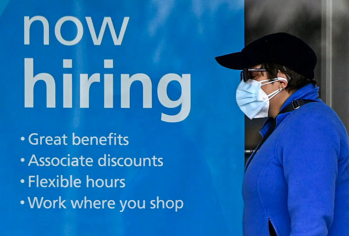 A woman walks past a "Now Hiring" sign in front of a store in Arlington, Va., on Jan. 13, 2022. (Olivier Douliery/AFP via Getty Images)