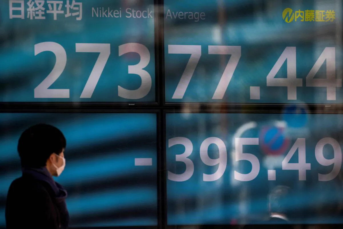 A pedestrian walks past an electronic quotation board displaying the Nikkei 225 index of the Tokyo Stock Exchange in Tokyo, on Jan. 21, 2022. (Behrouz Mehri/AFP via Getty Images)