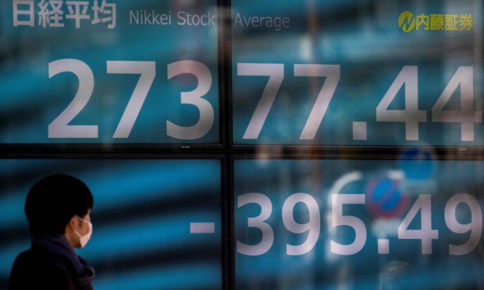 A pedestrian walks past an electronic quotation board displaying the Nikkei 225 index of the Tokyo Stock Exchange in Tokyo, on Jan. 21, 2022. (Behrouz Mehri/AFP via Getty Images)