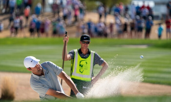 Scottie Scheffler plays from the green side bunker on the third as caddy J.Tedd Scott looks on during the final round of the WM Phoenix Open golf tournament at Scottsdale, Ariz., on Feb. 13, 2022. (Allan Henry/USA TODAY Sports via Field Level Media)
