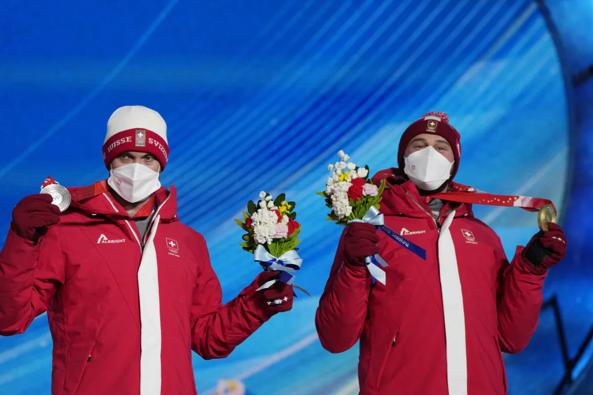 Silver medalist Switzerland's Alex Fiva (L) and Gold medalist Switzerland's Ryan Regez pose during a medal ceremony for the freestyle skiing men's cross competition at the 2022 Winter Olympics in Zhangjiakou, China on Feb. 18, 2022. (Alessandra Tarantino/AP Photo)