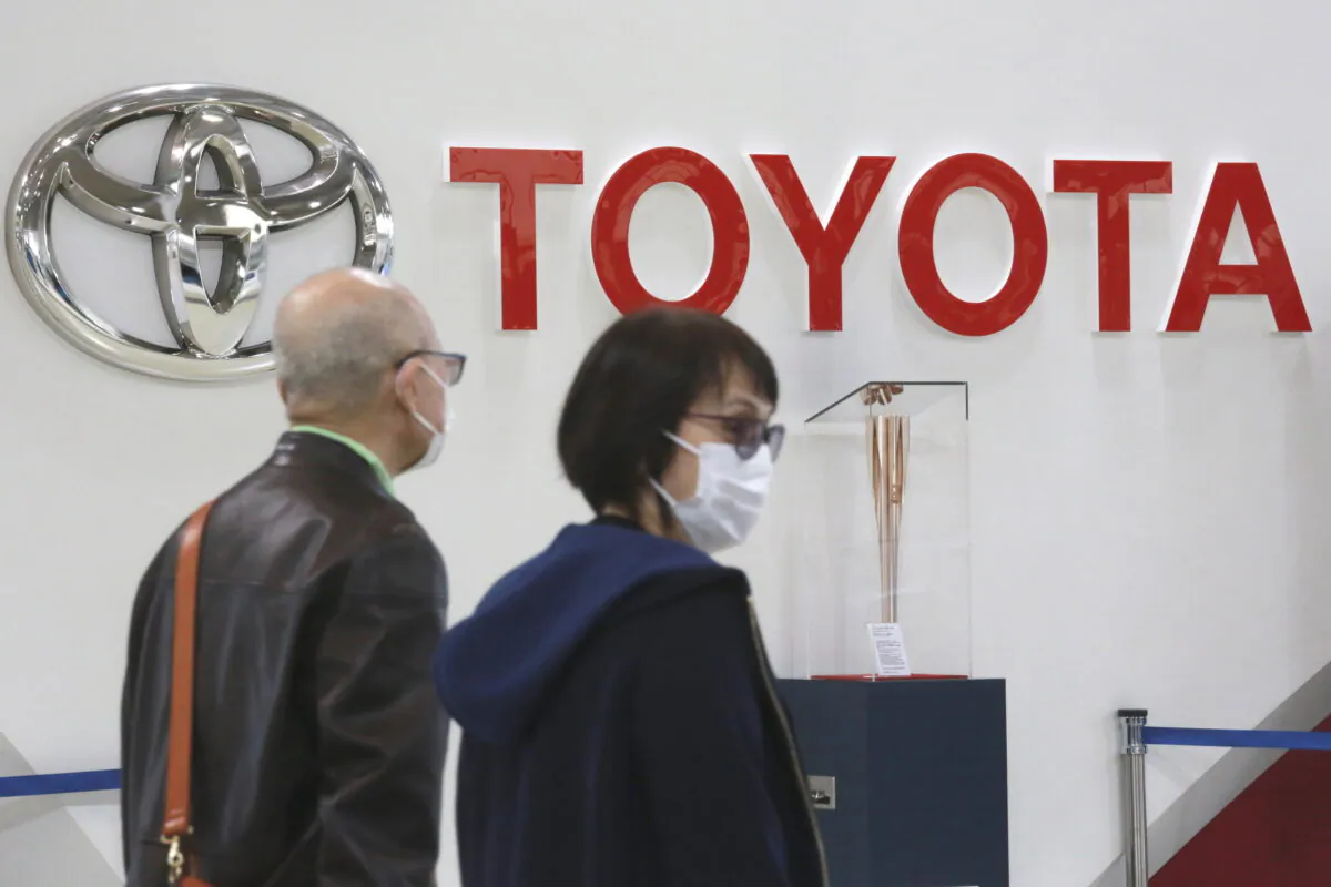 People walk past the logo of Toyota at a showroom in Tokyo on Oct. 18, 2021. (Koji Sasahara/AP Photo)