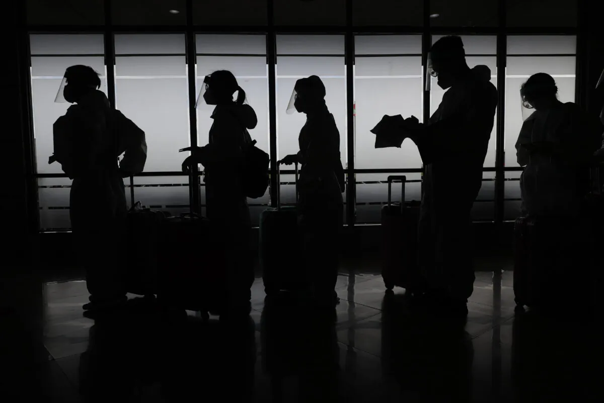 Foreign passengers wearing protective suits prepare for their flight to China at Manila's International Airport, Philippines, on Jan. 18, 2021. (Aaron Favila/AP Photo)