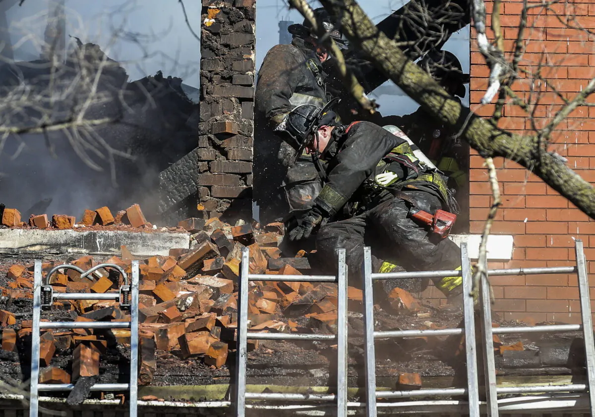A firefighter reacts after a pile of bricks falls on him from a window eve as crews work to extinguish the fire in the structure in St. Louis, Mo. on Jan. 13, 2022. (Colter Peterson/St. Louis Post-Dispatch via AP, File)