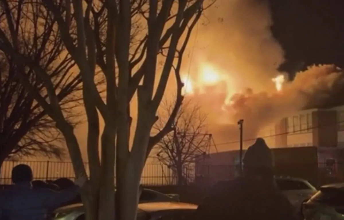 In this grab taken from video, bystanders watch as fire and smoke rise from the William Fox Elementary School, in Richmond, Va., on Feb. 11, 2022. (Lauren Serpa via AP)
