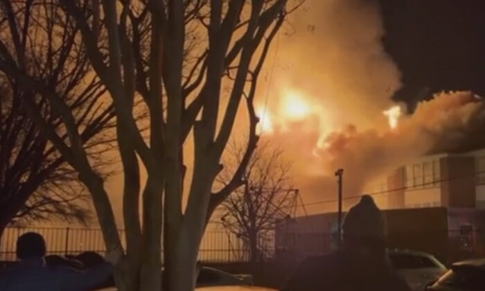 In this grab taken from video, bystanders watch as fire and smoke rise from the William Fox Elementary School, in Richmond, Va., on Feb. 11, 2022. (Lauren Serpa via AP)
