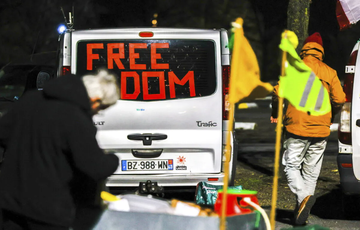 People walk by vehicles with banners and flags parked outside the city centre of Brussels, on Feb. 14, 2022. (Olivier Matthys/AP Photo)