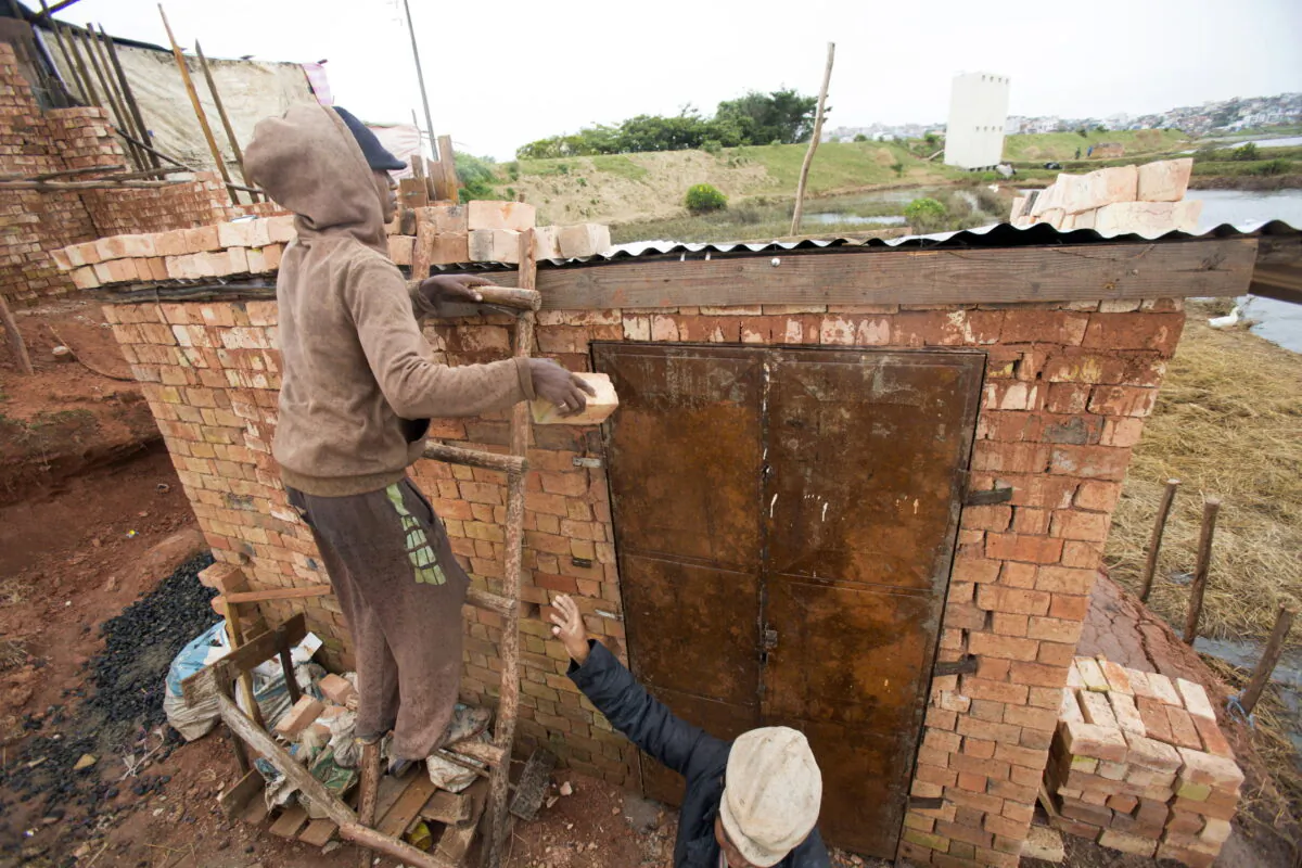 A man weighs down the roof of his home with bricks to stop it from flying away during bad weather in Antananarivo, Madagascar, on Feb. 5, 2022. (Alexander Joe/AP Photo)