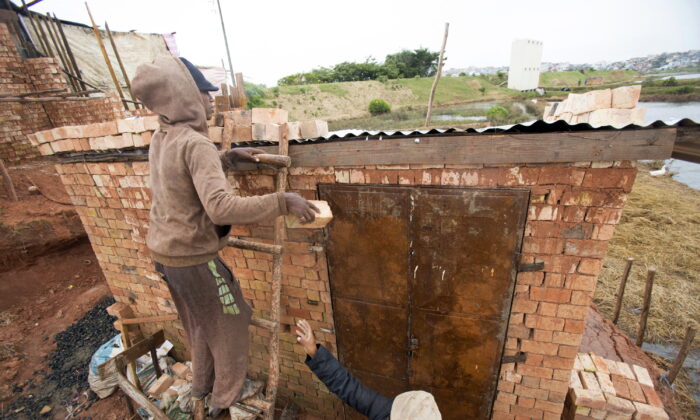 A man weighs down the roof of his home with bricks to stop it from flying away during bad weather in Antananarivo, Madagascar, on Feb. 5, 2022. (Alexander Joe/AP Photo)